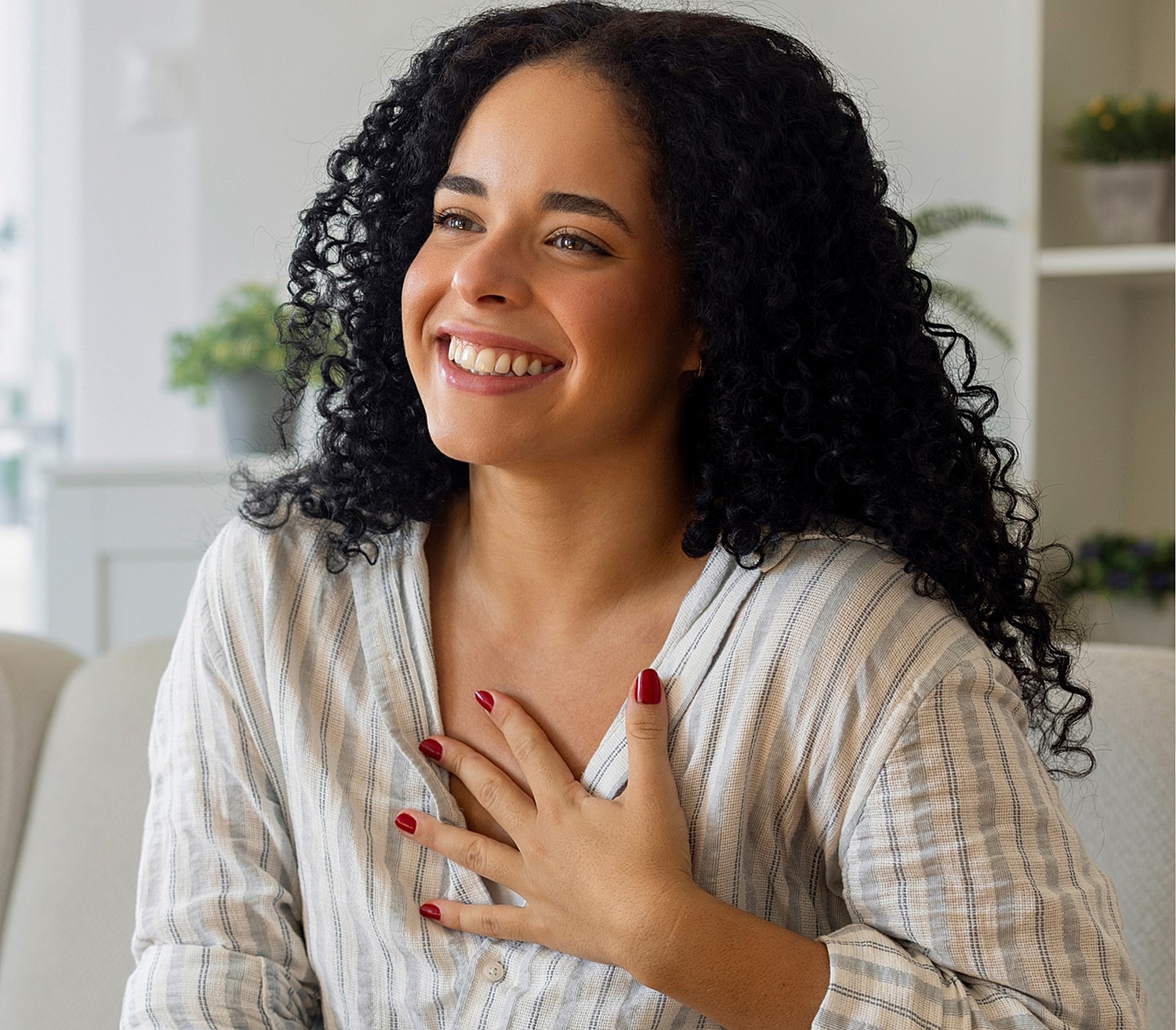 Smiling woman with curly hair, expressing joy.